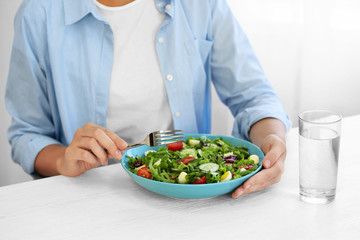Woman eating fresh delicious salad at table