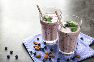 Two glasses of tasty smoothie, blueberries and almond on grey table