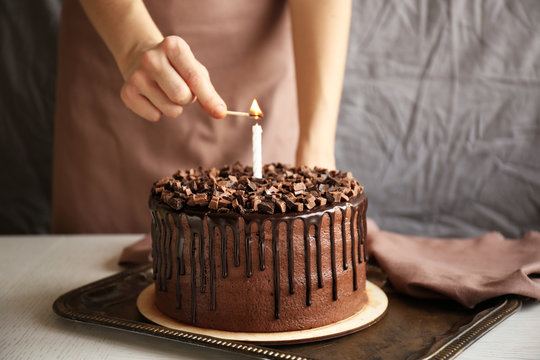 Woman lighting candle on chocolate cake