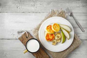 Cheesecakes with pear and milk on a white plate