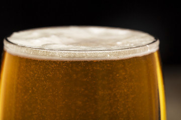 glass of beer with bubbles on black closeup.