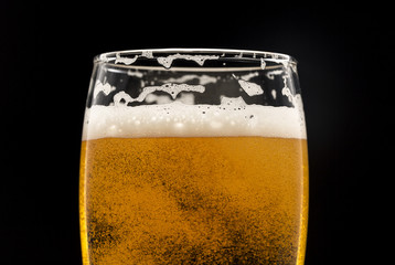 glass of beer with bubbles on black closeup.