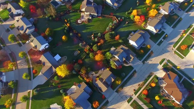 Tranquil idyllic wealthy Autumn neighborhood with frosty rooftops at sunrise, aerial view.
