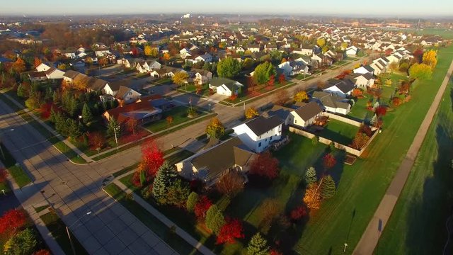 Tranquil idyllic wealthy Autumn neighborhood with frosty rooftops at sunrise, aerial view.