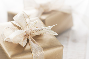 Golden gift boxes with beautiful ribbon and bow on a bright shiny background, holiday concept,...