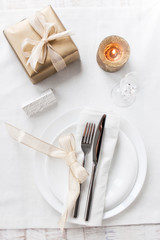 Beautifully elegant decorated table for holiday - wedding or valentine day with modern cutlery, bow, glass, candle and gift, top view