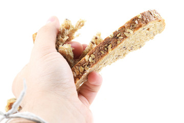 Man's hand crushing a slice of whole wheat bread
