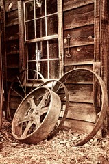 Fototapeta na wymiar Reflections of Yesterday. Vintage wagon wheels leaning against the side of a barn.