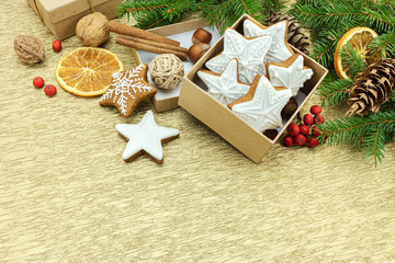 christmas gingerbread cookies in gift box, fir tree branches, nuts and spices on gold wrapping paper background