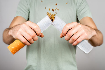 Quit smoking - male smoker breaking giant cigarette