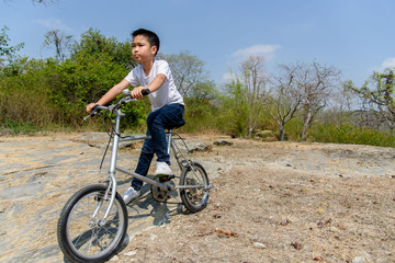 Fototapeta na wymiar Little boy ride bicycle on the rock road.