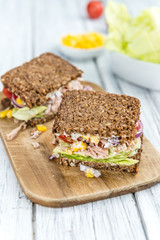 Wooden table with Tuna sandwich (on wholemeal bread; selective f