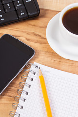 Mobile phone with notepad for writing notes and cup of coffee