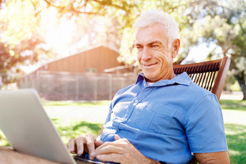 Senior man with notebook sitting in the park