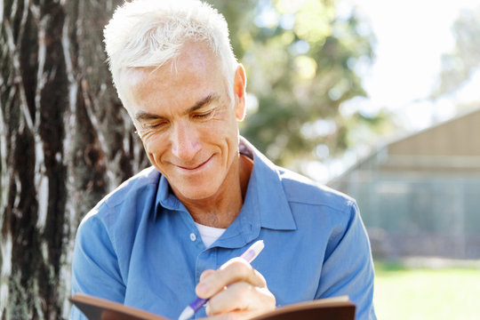 Senior man sittingin park while reading book