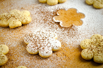 Homemade shortbread flower shape cookies with sugar powder on wooden table
