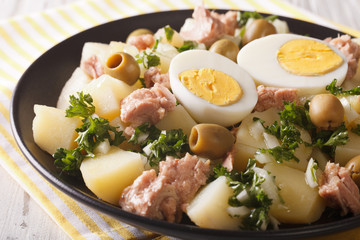 Spanish boiled potatoes with tuna, egg and olives close-up. horizontal