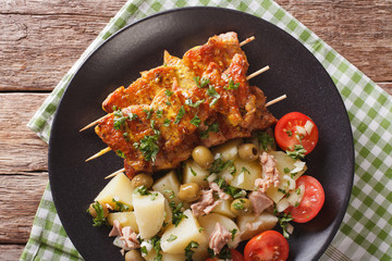 Spanish Food: kebab Pinchos Morunos and vegetables salad close-up. Horizontal top view