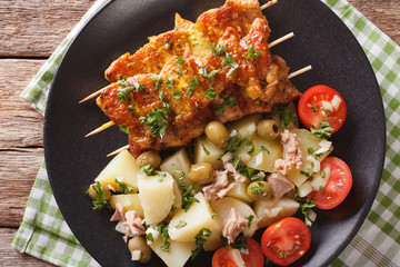 Spanish kebab Pinchos Morunos and salad Patatas Alinadas close-up. Horizontal top view