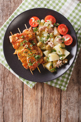 Spanish Pork Kabobs - Pinchos Morunos and Potatoes salad closeup. vertical top view