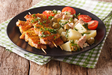 Spanish kebab Pinchos Morunos and salad Patatas Alinadas close-up. Horizontal