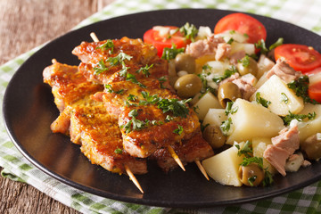 Spanish skewers Pinchos Morunos and potato salad with tuna closeup. horizontal