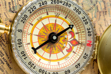 the old gold compass with cover on vintage map, macro background