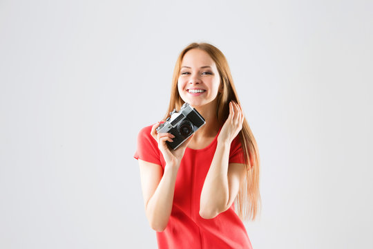 Smiling attractive young woman taking photos using old camera.