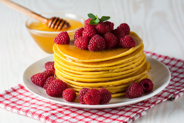 Fresh made delicious pancakes with berries, blackberries, raspberries, banana, honey and maple syrup. Healthy morning breakfast concept.