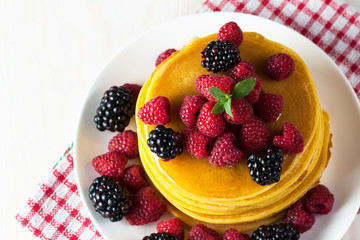 Fresh made delicious pancakes with berries, blackberries, raspberries, banana, honey and maple syrup. Healthy morning breakfast concept.