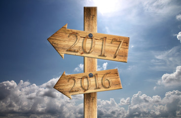 Wood sign of 2016 and 2017 in in left on blue sky background.