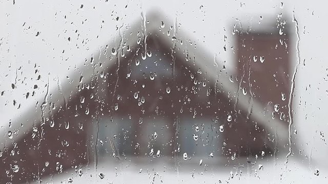 Snow falls on the background of the window of a private house
