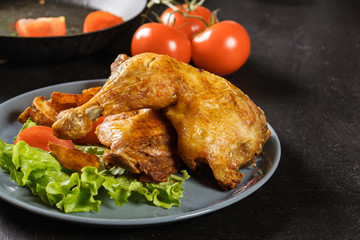 Roasted chicken legs with potato wedges and tomatoes