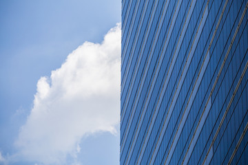 Fototapeta na wymiar Glass wall in modern office building with blue sky and clouds