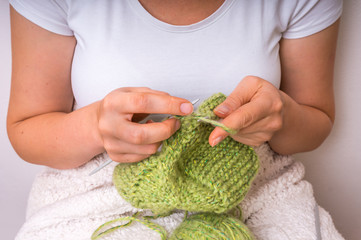 Female hands with needles knitting with green wool