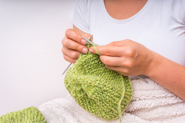 Female hands with needles knitting with green wool