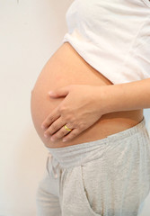 Pregnant women touch hand to belly.