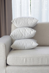 Fototapeta na wymiar Stacking white pillows at the corner of sofa in living room