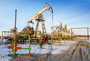 Group of oil pumps and wellheads in the oilfield during winter. Oil and gas concept.