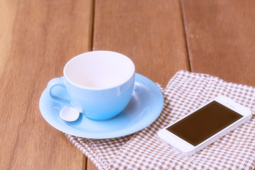 Blue coffee cup and smart phone on wooden table