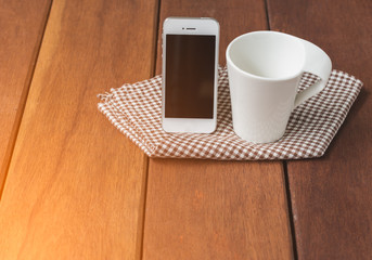 White coffee cup and smart phone on wooden table