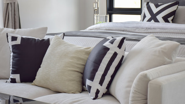 Black and white graphic printed pillow on off white sofa next to bed