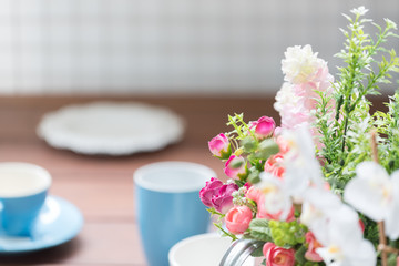 Blue and white coffee cups on wood table with flower bouquet dec
