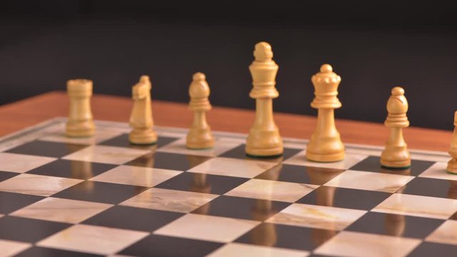 Chess pieces appearing on chessboard in stop motion film clip. Strategy game with two opposing sides.