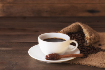 Cup of coffee and sugar stick on old wooden table.