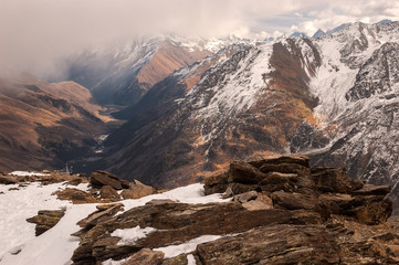 Ski resort Cheget. Low clouds block the view of  Main Caucasian ridge and Baksan gorge. Textured stones with lichen covered with snow in the foreground. Caucasus