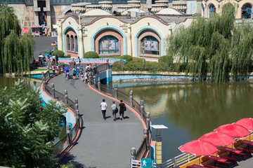 People walking on twisty bridge in the amusement park.