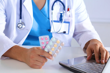 Male medicine doctor hands hold jar of pills and type something on laptop computer keyboard. Panacea life save, prescribing treatment, legal drug store, take stock, consumption statistics concept