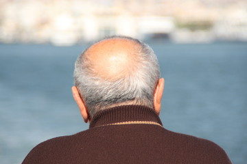 Old, bald man watching the sea
