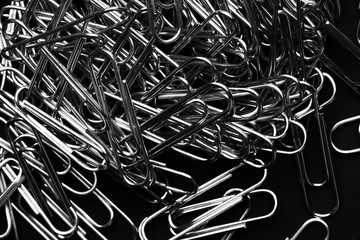 Heap of paper clips - Detail closeup abstract stationery on black clolor background. with copy space